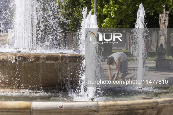 Tourist, visitors and locals are walking past Syntagma Square with the famous fountain during a heatwave in Athens with the high temperature...