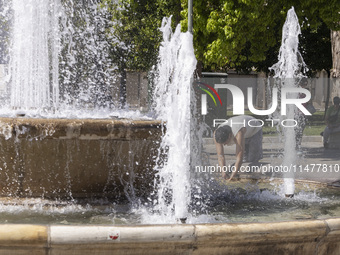 Tourist, visitors and locals are walking past Syntagma Square with the famous fountain during a heatwave in Athens with the high temperature...