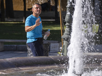 Tourist, visitors and locals are walking past Syntagma Square with the famous fountain during a heatwave in Athens with the high temperature...