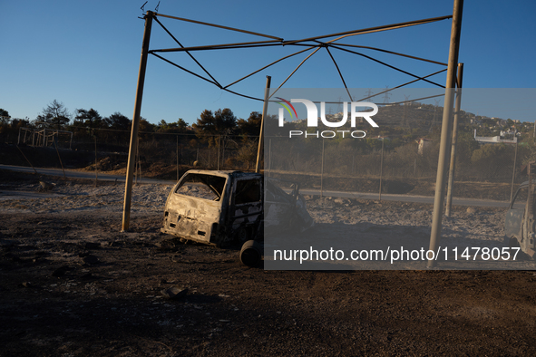 A destroyed car is sitting in a lumber warehouse in the Vrilissia area, due to the fire that broke out in Athens, Greece, on August 11, 2024...