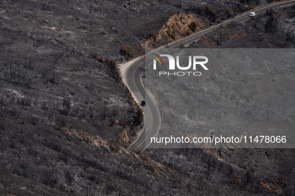 A car is driving through a road in the burnt Penteli mountain, a day after the devastating fire that broke out in Athens, Greece, on August...