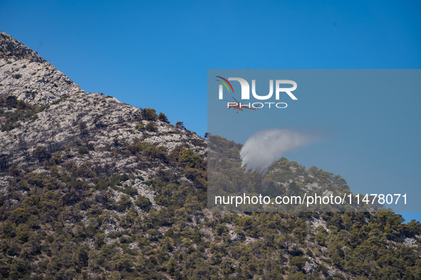 A firefighting helicopter is operating to extinguish flare-ups after the fire that broke out in Athens, Greece, on August 11, 2024, in the N...