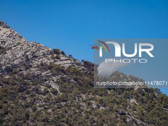 A firefighting helicopter is operating to extinguish flare-ups after the fire that broke out in Athens, Greece, on August 11, 2024, in the N...