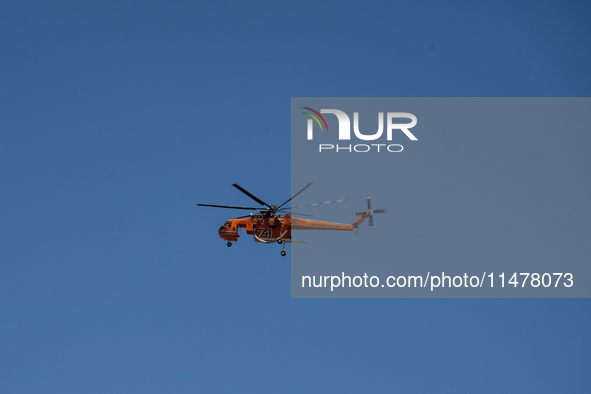 A firefighting helicopter is operating to extinguish flare-ups after the fire that broke out in Athens, Greece, on August 11, 2024, in the N...