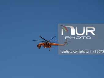 A firefighting helicopter is operating to extinguish flare-ups after the fire that broke out in Athens, Greece, on August 11, 2024, in the N...