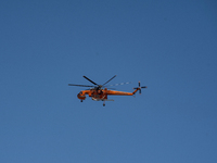 A firefighting helicopter is operating to extinguish flare-ups after the fire that broke out in Athens, Greece, on August 11, 2024, in the N...