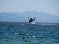 A firefighting helicopter is collecting water from the sea in Nea Makri, Greece, on August 14, 2024, while battling the flare-ups of the fir...