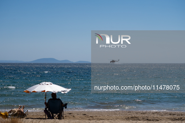 A firefighting helicopter is collecting water from the sea in Nea Makri, Greece, on August 14, 2024, while battling the flare-ups of the fir...