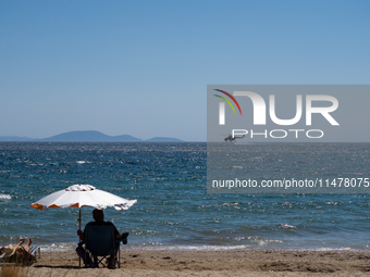 A firefighting helicopter is collecting water from the sea in Nea Makri, Greece, on August 14, 2024, while battling the flare-ups of the fir...