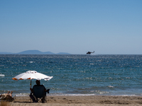 A firefighting helicopter is collecting water from the sea in Nea Makri, Greece, on August 14, 2024, while battling the flare-ups of the fir...