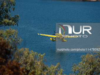 A firefighting plane is collecting water from Marathon Lake to extinguish flare-ups in Marathon, Greece, on August 14, 2024 (