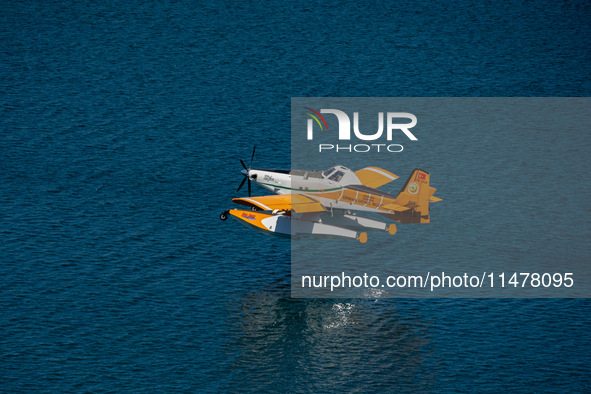 A firefighting plane from Turkey is collecting water from Marathon Lake to combat the flare-ups in Marathon, Greece, on August 14, 2024 