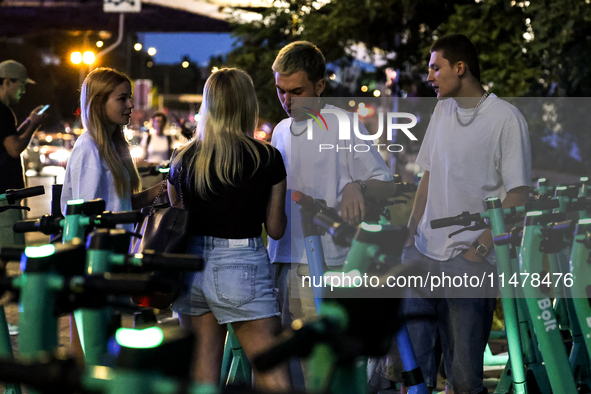 Young adults collect Bolt electric commercial scooter available for public commute in central Warsaw, the capital of Poland on August 14, 20...