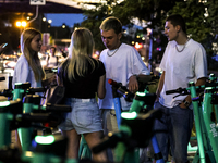 Young adults collect Bolt electric commercial scooter available for public commute in central Warsaw, the capital of Poland on August 14, 20...