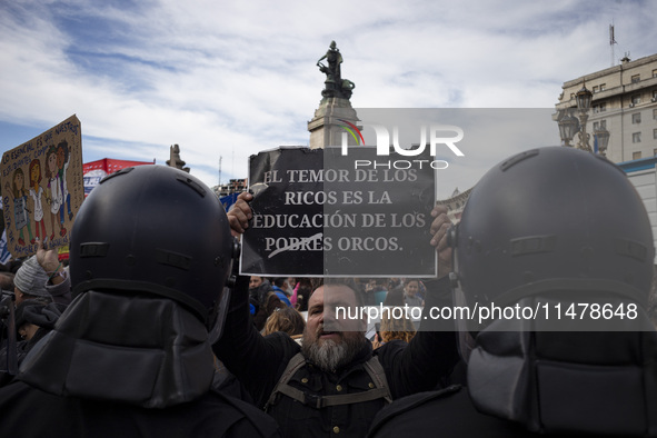 The teacher is showing a poster in defense of education to the Federal Police  during a protest of Education Workers' Union in Buenos Aires,...