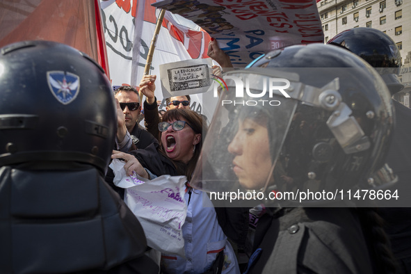 The teacher is showing a poster in defense of education to the Federal Police during a protest of Education Workers' Union in Buenos Aires,...