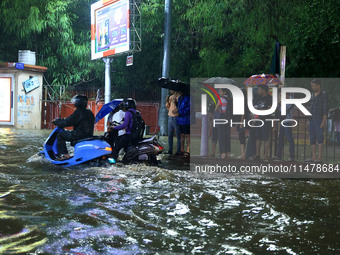 Vehicles and locals are moving through the waterlogged road at Narayan Singh Circle following heavy monsoon rains, in Jaipur, Rajasthan, Ind...