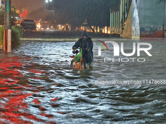 Locals are moving through the waterlogged road at Narayan Singh Circle following heavy monsoon rains, in Jaipur, Rajasthan, India, on August...