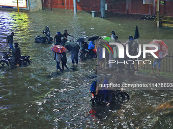 Vehicles and locals are moving through the waterlogged road at Narayan Singh Circle following heavy monsoon rains, in Jaipur, Rajasthan, Ind...