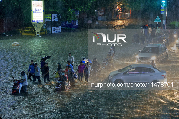 Vehicles and locals are moving through the waterlogged road at Narayan Singh Circle following heavy monsoon rains, in Jaipur, Rajasthan, Ind...