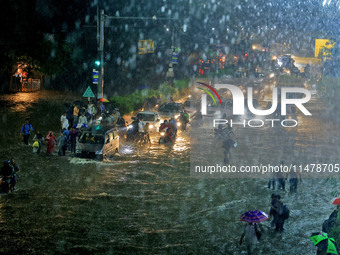 Vehicles and locals are moving through the waterlogged road at Narayan Singh Circle following heavy monsoon rains, in Jaipur, Rajasthan, Ind...