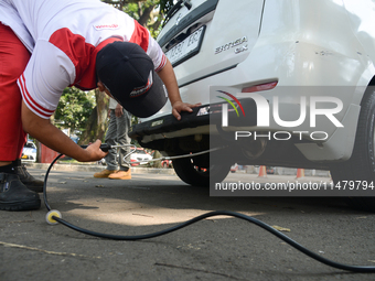 An officer is testing a probe in the exhaust pipe of a vehicle as part of an exhaust emissions test in Bogor, West Java, Indonesia, on Augus...