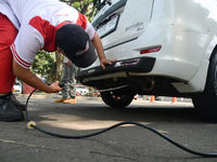 An officer is testing a probe in the exhaust pipe of a vehicle as part of an exhaust emissions test in Bogor, West Java, Indonesia, on Augus...