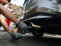 An officer is testing a probe in the exhaust pipe of a vehicle as part of an exhaust emissions test in Bogor, West Java, Indonesia, on Augus...