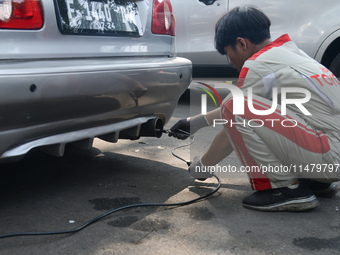 An officer is testing a probe in the exhaust pipe of a vehicle as part of an exhaust emissions test in Bogor, West Java, Indonesia, on Augus...