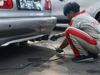 An officer is testing a probe in the exhaust pipe of a vehicle as part of an exhaust emissions test in Bogor, West Java, Indonesia, on Augus...