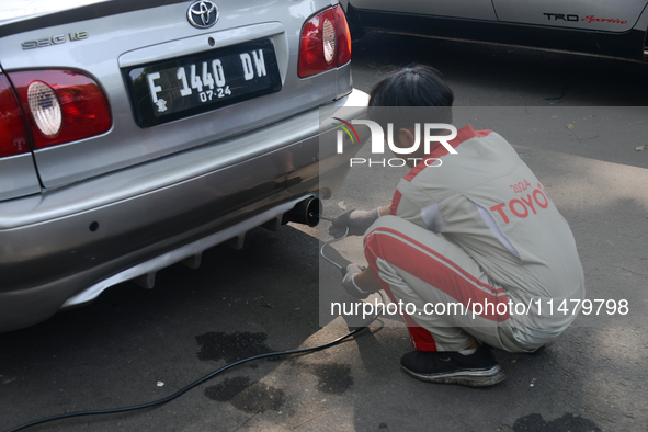 An officer is testing a probe in the exhaust pipe of a vehicle as part of an exhaust emissions test in Bogor, West Java, Indonesia, on Augus...