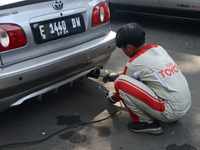 An officer is testing a probe in the exhaust pipe of a vehicle as part of an exhaust emissions test in Bogor, West Java, Indonesia, on Augus...