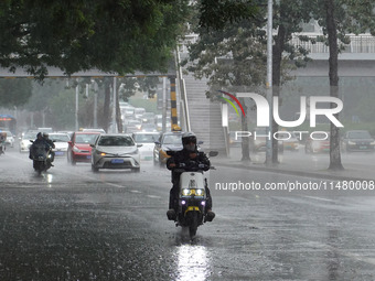 Vehicles and pedestrians are making their way through the rain on the East Third Ring Road in Beijing, China, on August 15, 2024. (