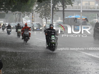 Vehicles and pedestrians are making their way through the rain on the East Third Ring Road in Beijing, China, on August 15, 2024. (