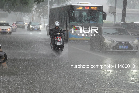 Vehicles and pedestrians are making their way through the rain on the East Third Ring Road in Beijing, China, on August 15, 2024. 