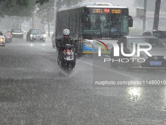 Vehicles and pedestrians are making their way through the rain on the East Third Ring Road in Beijing, China, on August 15, 2024. (