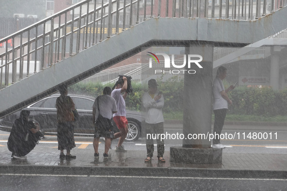 Pedestrians are taking shelter from the rain at the East Third Ring Road in Beijing's Chaoyang district in Beijing, China, on August 15, 202...