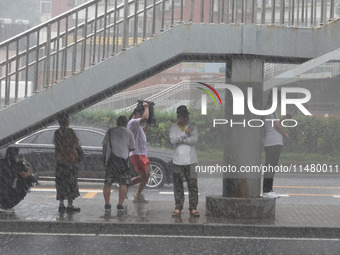 Pedestrians are taking shelter from the rain at the East Third Ring Road in Beijing's Chaoyang district in Beijing, China, on August 15, 202...