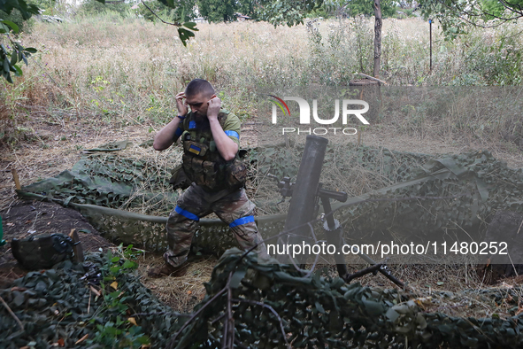 A serviceman of the 24th King Daniel of Galicia Separate Mechanized Brigade is covering his ears while firing a mortar at the positions of R...