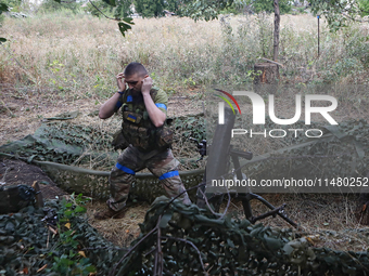 A serviceman of the 24th King Daniel of Galicia Separate Mechanized Brigade is covering his ears while firing a mortar at the positions of R...