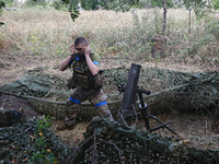 A serviceman of the 24th King Daniel of Galicia Separate Mechanized Brigade is covering his ears while firing a mortar at the positions of R...