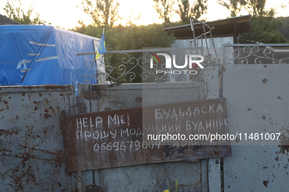 A note is asking for help with getting a modular house on the fence outside a house in Kamianka village, Kharkiv region, Ukraine, on August...