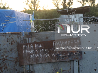 A note is asking for help with getting a modular house on the fence outside a house in Kamianka village, Kharkiv region, Ukraine, on August...