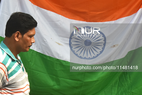 A person is passing next to the national flag of India on the occasion of Independence Day in Kolkata, India, on August 15, 2024. 