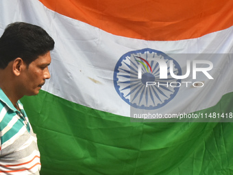 A person is passing next to the national flag of India on the occasion of Independence Day in Kolkata, India, on August 15, 2024. (