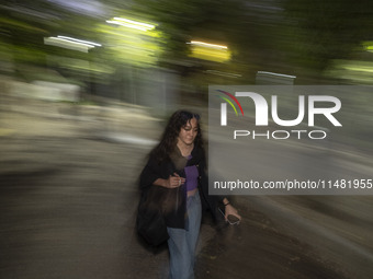 A young woman who is not wearing a mandatory headscarf is walking along a park in central Tehran, Iran, on August 15, 2024. (