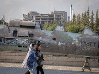 Two young Iranian women are walking past an Iraqi crashed fighter jet at the War Museum at a park in central Tehran, Iran, on August 15, 202...