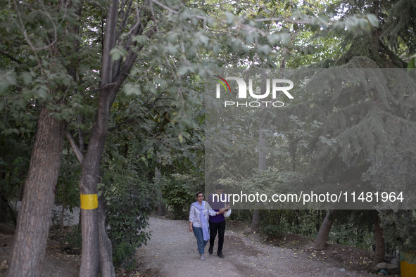 An Iranian couple is walking together along a park in central Tehran, Iran, on August 15, 2024. 