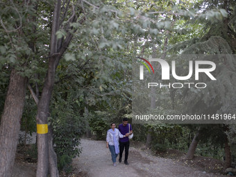 An Iranian couple is walking together along a park in central Tehran, Iran, on August 15, 2024. (