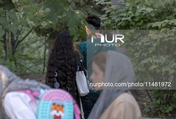 An Iranian couple is walking together along a park in central Tehran, Iran, on August 15, 2024. 